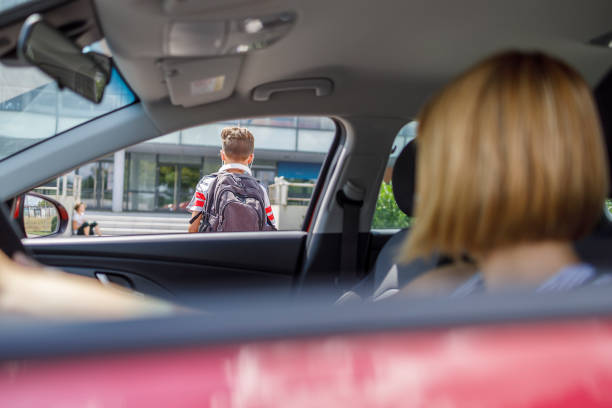 Woman in a car observing her son entering school Boy with school bag going towards school and his mother sitting in the car and waiting for him to enter for his classes teenager boy driving stock pictures, royalty-free photos & images