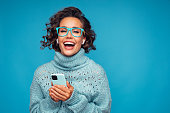 Beautiful woman standing in front of blue background with smart phone