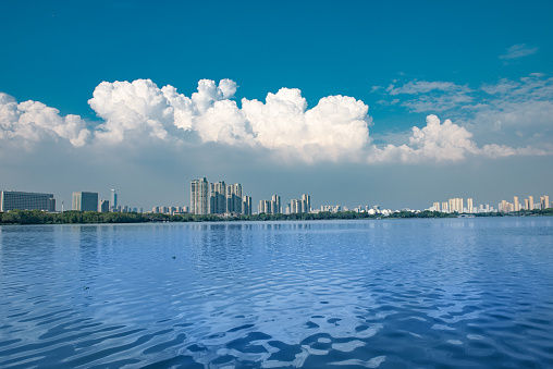 Under the clear sky, overlooking the city buildings in front of the blue microwave lake