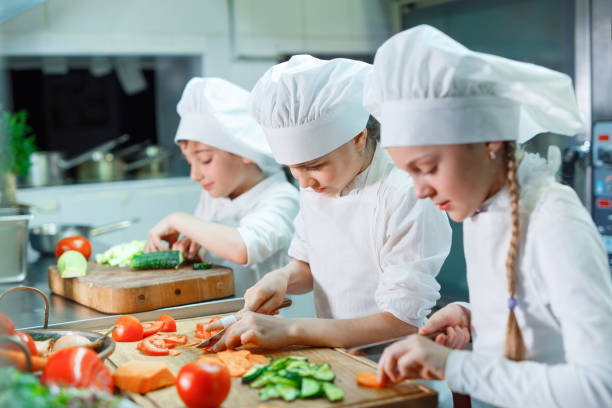 Children grind vegetables in the kitchen of a restaurant. stock photo