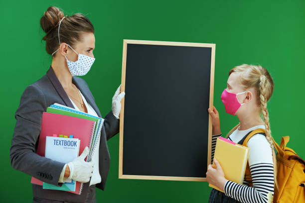 istock modern female teacher and pupil showing blank black board 1268186621