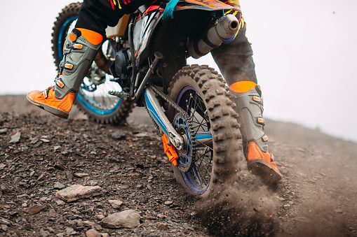 Close-up of mountain motocross race in dirt track in day time. Concept focus of during an acceleration in action sport.