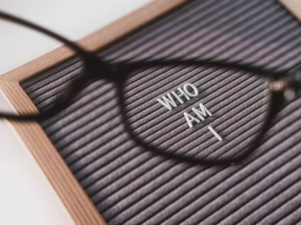 istock Top view on letterboard with words WHO AM I through eyeglasses. Flat lay concept of psychological self-regulation or gender identity. Social psychological issue. Closer look on psychological problems. 1268188513