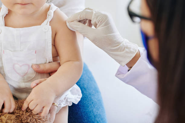 Flu or coronavirus vaccine Doctor in rubber gloves wiping injection site on arm of little girl before vaccinate her for coronavirus vaccination stock pictures, royalty-free photos & images