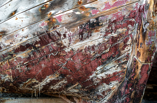 Close-up of weathered paint on the hull of an old wooden fishing boat