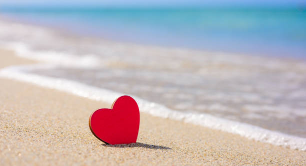 istock A red little heart stands on a sandy beach. 1268203470