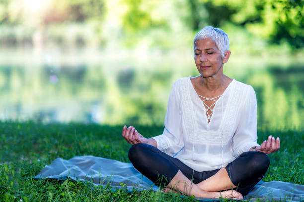 istock Senior woman meditating by the water 1268203732