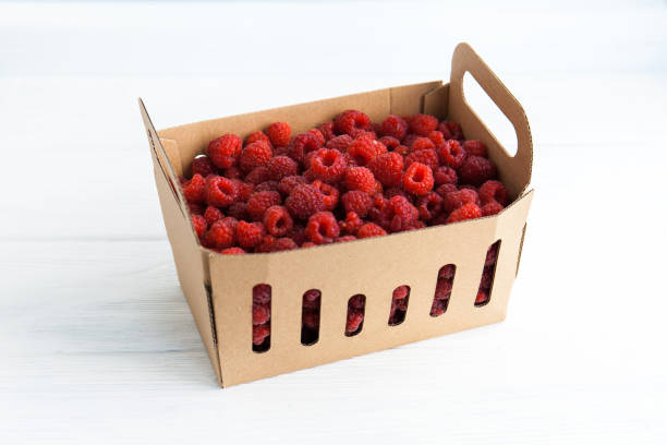 istock Fresh raspberries in a box on a white table 1268205858
