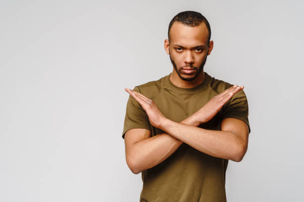 istock african american young man gesturing STOP with his hands crossed over light grey background 1268206056
