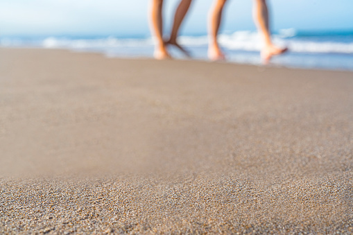 Summer backgrounds: blurred couple walking on the beach. Useful copy space available for text and/or logo. Predominant color is blue. High resolution 42Mp studio digital capture taken with SONY A7rII and Zeiss Batis 40mm F2.0 CF lens