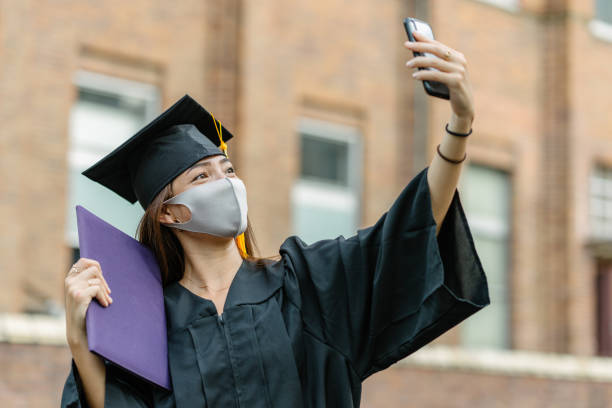 istock Female student holding her diploma and using her smart phone in campus 1268214125