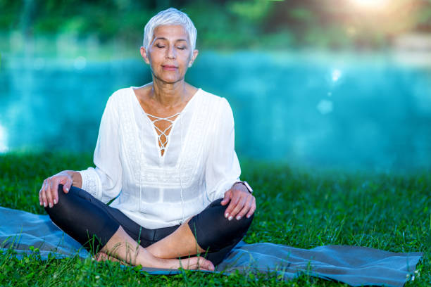 istock Senior woman meditating by the water 1268215579