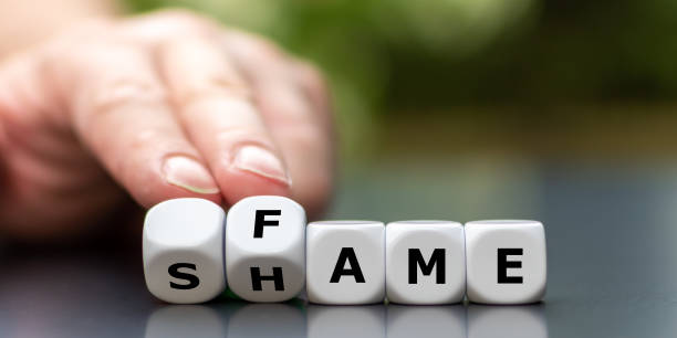 istock Hand turns dice and changes the word shame to fame. 1268217358