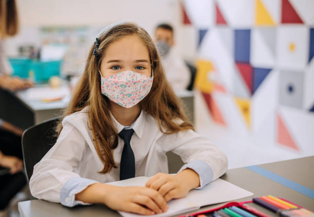 istock Cute little girl posing in a primary school with a face mask on 1268217841