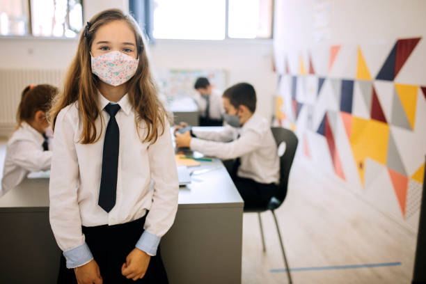 istock Cute little elementary school girl posing with a face mask on 1268219883