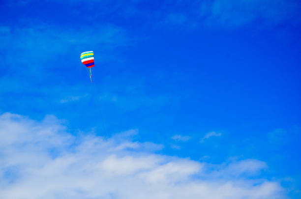 colorful paragliding in front of a blue sky with white clouds