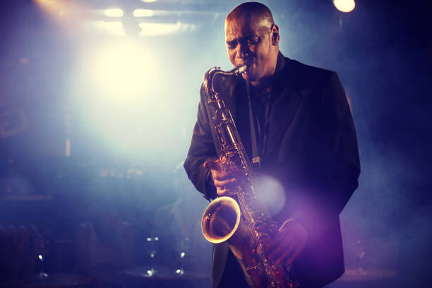 Man Playing Saxophone on Stage Man Playing Saxophone on Stage performer stock pictures, royalty-free photos & images