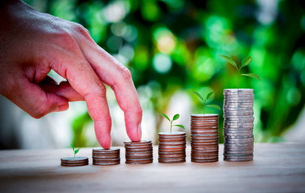 istock Male hand stacking coins same stair for the first step like growing for the future, education, home, loan and child on green bokeh background. Plant growing on coins. 1268227175