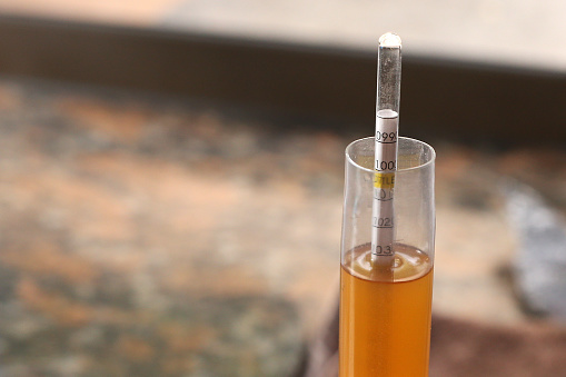 A Close up view while Measuring the alcohol content with a Hydrometer in a glass tube of beer.