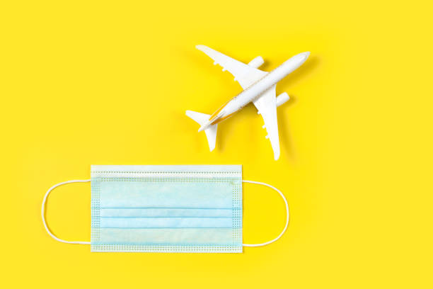 istock Plane model and face mask on a yellow background. Flight impact of coronavirus (COVID-19) concept. 1268233066