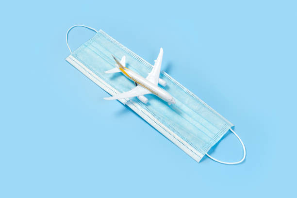 istock Plane model and face mask on a blue background. Flight impact of coronavirus (COVID-19) concept. 1268233094