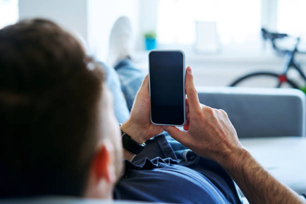 istock Closeup of relaxed man using mobile phone on the couch at home 1268238534