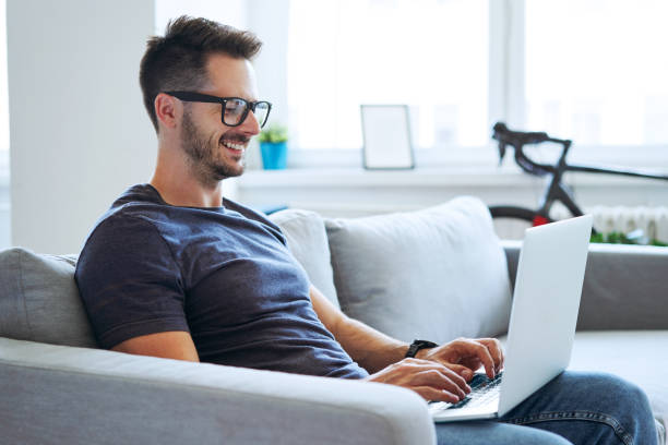 istock Satisfied man sitting on couch using laptop working from home 1268238642