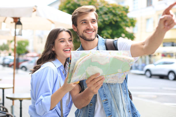 istock Beautiful young couple holding a map and smiling while standing outdoors. 1268241992