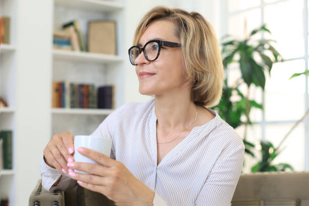 istock Mature blond woman in couch having a tea or coffee. 1268242035
