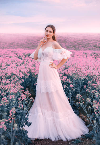 glamour woman bride fashion model. white long vintage wedding dress. princess medieval lady in elegant bridal clothes trendy boho style. meadow pink flowers. spring nature flowering blooming field - bride wedding fashion evening gown imagens e fotografias de stock