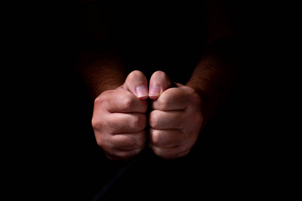 istock Male hands emerging from the darkness. Hands on a black background. 1268244373
