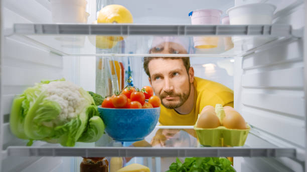 istock Inside Kitchen Fridge: Young Disappointed Man Looks inside the Fridge. Man Found Nothing for His Snack Time. Point of View POV Shot from Refrigerator full of Healthy Food 1268244672
