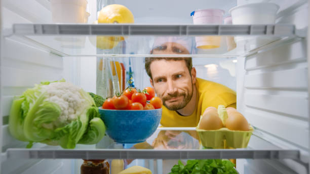 istock Inside Kitchen Fridge: Young Disappointed Man Looks inside the Fridge. Man Found Nothing for His Snack Time. Point of View POV Shot from Refrigerator full of Healthy Food 1268244678