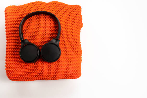 istock Wireless headphones in black and orange sweater on white background Modern technology Top view flat lay 1268245903