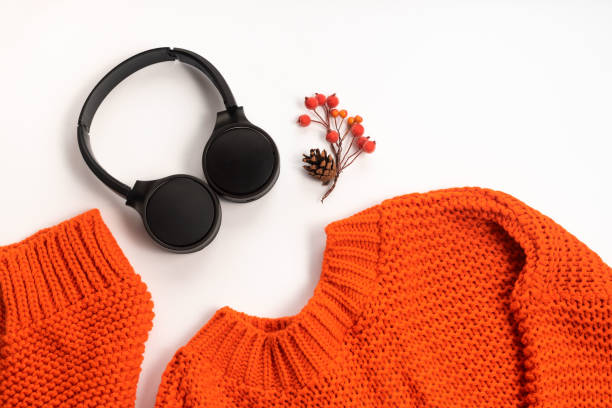 istock Wireless headphones in black and orange sweater on white background Modern technology Top view flat lay 1268245904