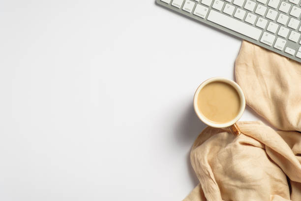 istock White office desk table with coffee cup, computer keyboard, beige scarf . Top view with copy space, minimalist style. 1268249526