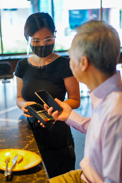 istock Senior Asian man making a contactless payment in a restaurant. 1268254878