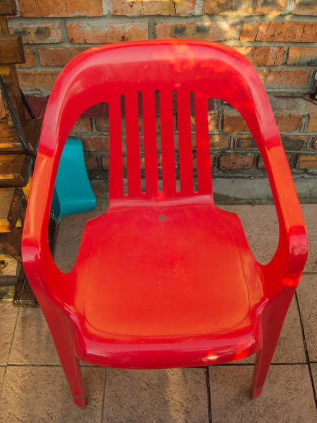 One red plastic chair against an old brick wall, outdoors.