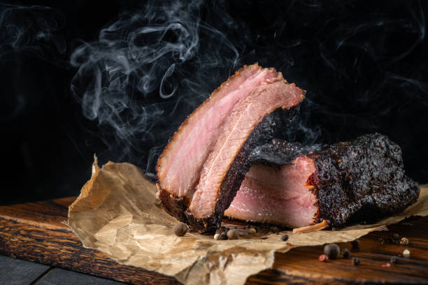 Smoky sliced beef brisket with dark crust from classic Texas smokehouse on a dark background Smoky sliced beef brisket with dark crust from classic Texas smokehouse on a dark background brisket photos stock pictures, royalty-free photos & images