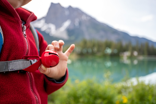 Happy Young Cute Redhead Boy Walking on Trail at Emerald Lake in Summer in Yoho National Park, Canada. He is wearing a bear bell on him.