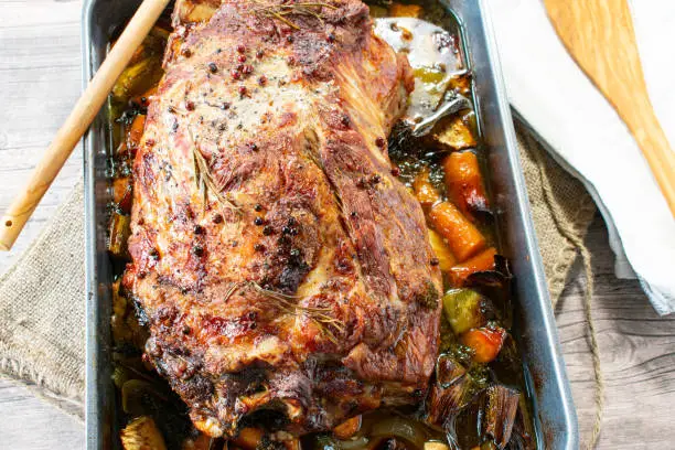 fresh and homemade roasted pork from a pork neck. Cooked with root vegetables in a baking pan for a big dinner