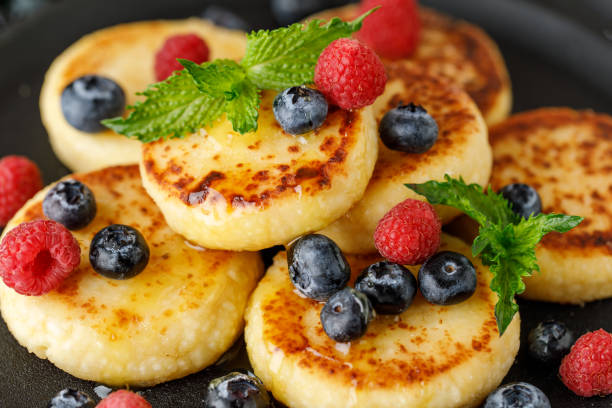 istock Cottage cheese pancakes with raspberry and blueberry in pan on rustic background, breakfast or lunch 1268260503