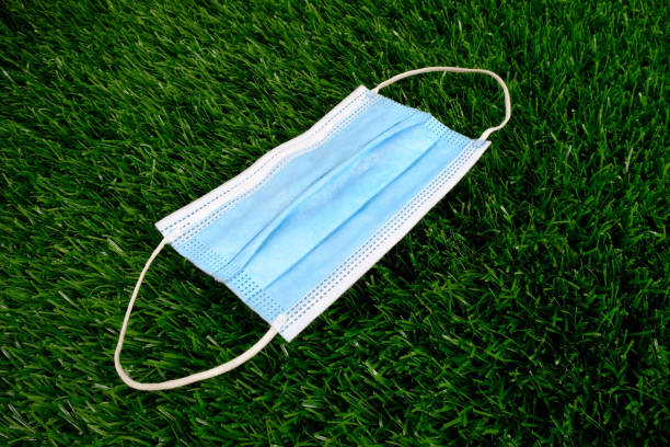 istock blue medical mask on green grass 1268260591