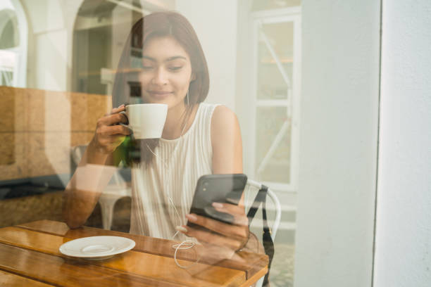 istock Young latin woman using phone at coffee shop. 1268261755