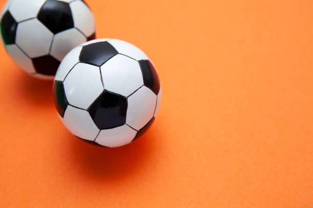 istock Mini soccer balls on an orange surface with copy space 1268261986