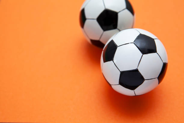 istock Mini soccer balls on an orange surface with copy space 1268262202