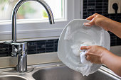 Young woman washing dishes with a sponge