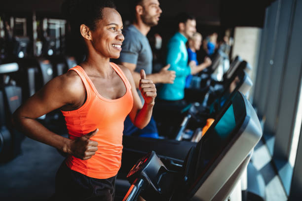 Happy woman smiling and working out in gym Happy beautiful woman smiling and working out in gym treadmill photos stock pictures, royalty-free photos & images
