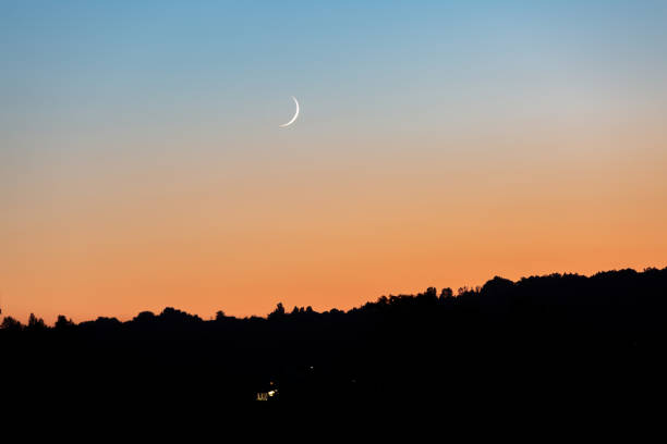 istock A young moon on an orange-blue sunset sky over a dark forest. Horizontal orientation. High quality photo 1268271746