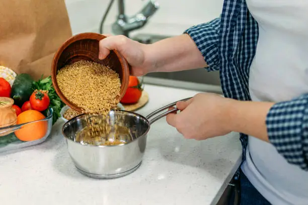 Woman is cooking Ancient Grains Porridge. Heirloom heritage Ancient grains on home kitchen. Health, vegetarian food, dieting.